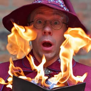 man in wizard hat behind flames