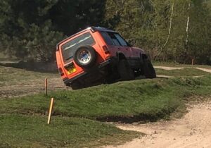 red 4x4 on a grass hill