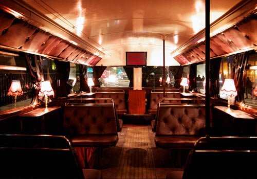 inside double decker bus with plush seats and lighting at tables