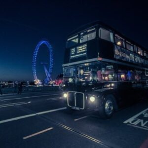 London bus at night on London Bridge with the Big wheel lit up in blue in background