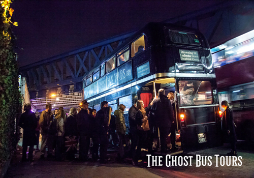 people queuing to get on black bus at night for a ghost tour