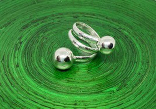 silver ring with silver balls on green background