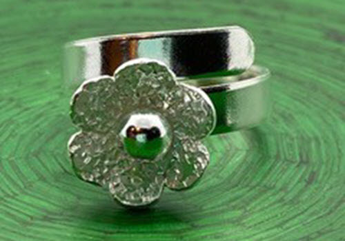 silver ring with daisy on green background