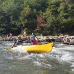 two people in yellow boat on river rapids