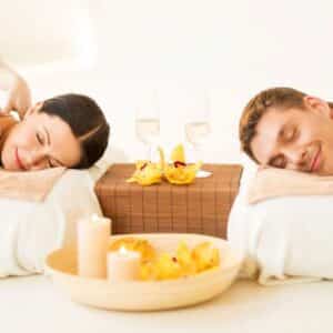 woman and man heads on pillow two glasses candles and wooden bowl