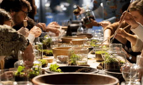 men and women sitting at table adding plants to fermentarium jar